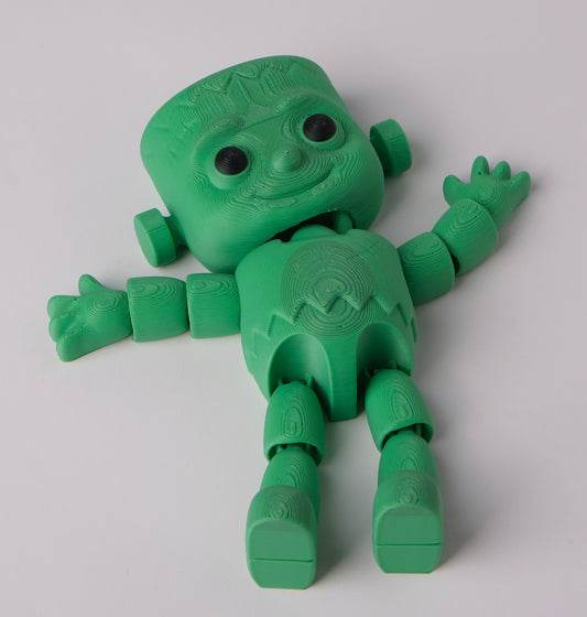 A green 3D-printed articulated toy figure with a blocky, stylized head, textured limbs.