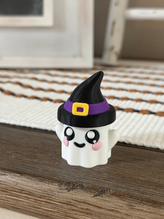 Cute ghost figurine with rosy cheeks wearing a black witch hat with a purple band and yellow buckle.